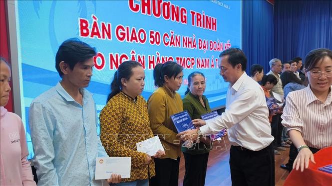 Trao bảng tượng trưng và quà cho người dân được nhận nhà mới. Ảnh: Huỳnh Phúc Hậu - TTXVN