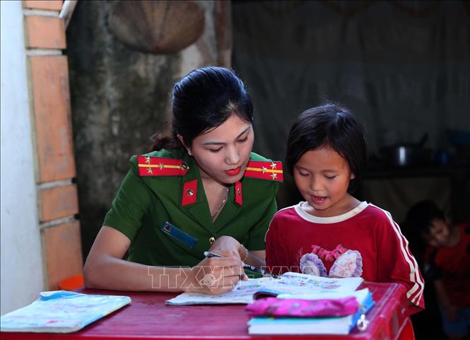 Cán bộ Công an xã Văn Hải hướng dẫn, kèm cặp các em nhỏ học bài trong chương trình “Cùng em đến trường” do Công an xã đỡ đầu. Ảnh: Trọng Đức - TTXVN