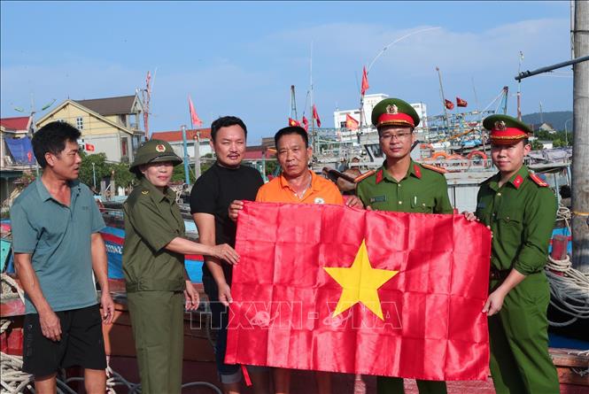 Công an xã Văn Hải tặng cờ Tổ quốc cho ngư dân chuẩn bị những chuyến ra khơi đánh bắt hải sản. Ảnh: Minh Khôi (TTXVN phát)