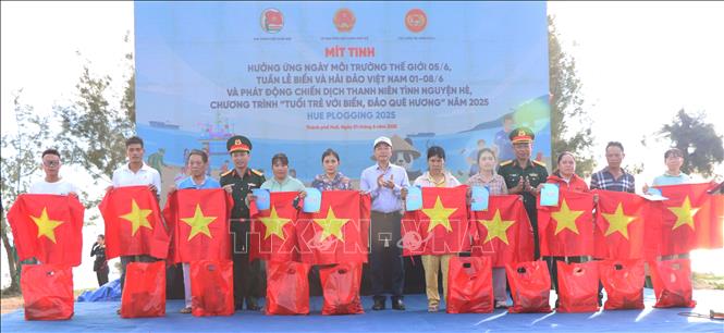 Trao tặng cờ Tổ quốc, áo phao và quà cho các gia đình ngư dân trên địa bàn. Ảnh: Mai Trang - TTXVN