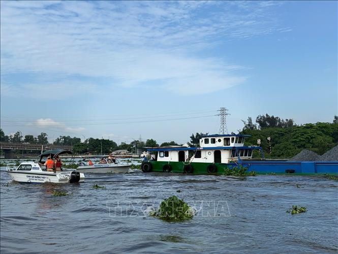 Lực lượng Cảnh sát đường thủy Long An kiểm tra chủ phương tiện vận chuyển khoáng sản trên sông Vàm Cỏ Đông. Ảnh: TTXVN phát