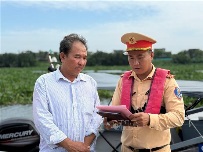 Lực lượng Cảnh sát đường thủy Long An kiểm tra chủ phương tiện vận chuyển khoáng sản trên sông Vàm Cỏ Đông. Ảnh: TTXVN phát