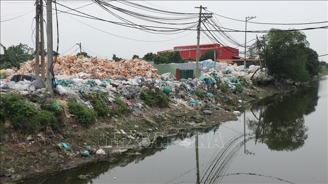 Rác thải nhựa của thôn Minh Khai được tập kết ngay cạnh bờ sông, gây ô nhiễm nghiêm trọng môi trường nguồn nước. Ảnh: Mạnh Khánh-TTXVN                              