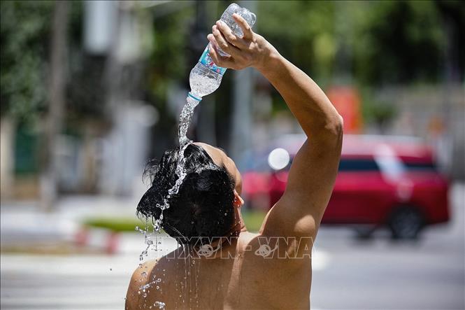 Một người lao động tự dội nước làm mát ngay trên hè phố Đại lộ Thịnh Lang, thành phố Hòa Bình. Ảnh: Trọng Đạt - TTXVN