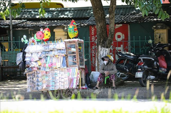 Những người phụ nữ bán hàng rong chọn ngồi nghỉ dưới tán cây trong khi bên ngoài nhiệt độ hiện là khoảng 40 độ C. Ảnh: Trọng Đạt - TTXVN