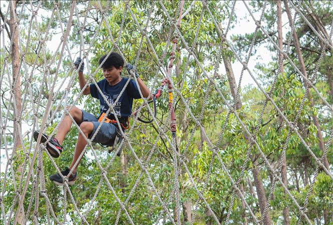 A visitor enjoys a high rope course while marvelling at the majestic waterfall scenery and stunning mountainous nature. VNA Photo: Hoàng Hiếu