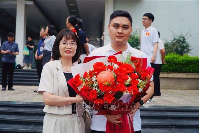Giáo viên lãnh đội và em Đỗ Trung Kiên tại buổi lễ xuất quân của đoàn Việt Nam. Ảnh: TTXVN