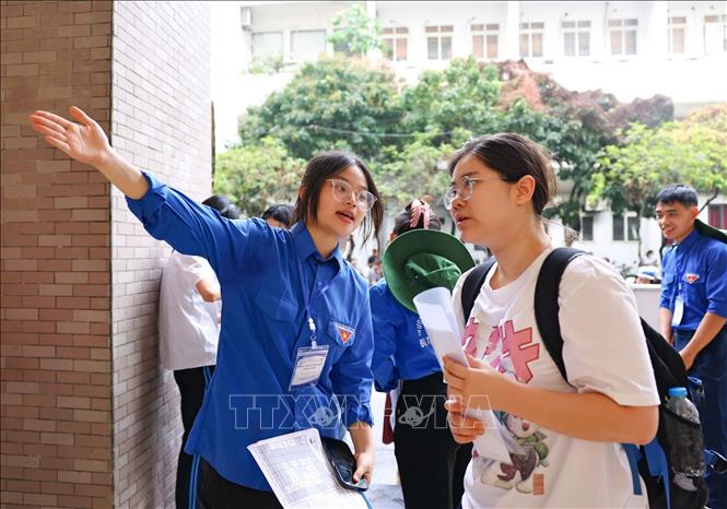 Thanh niên tình nguyện hỗ trợ, hướng dẫn phụ huynh và thí sinh tìm đến điểm thi, phòng thi. Ảnh: Thanh Tùng - TTXVN