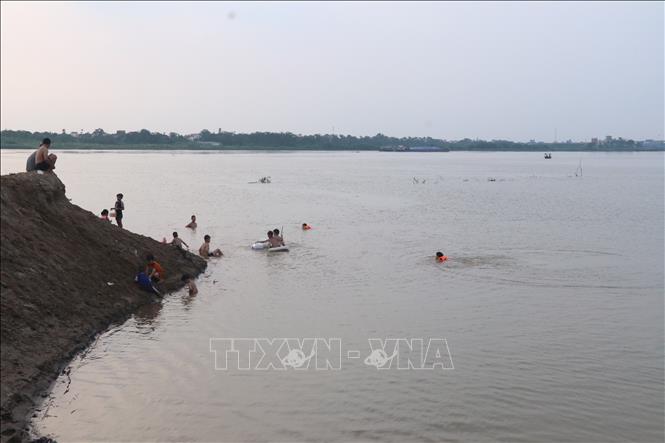 Nhiều trẻ nhỏ vô tư tắm, lội ở sông Hồng đoạn bến phà Yên Lệnh cũ, tiềm ẩn tai nạn đuối nước. Ảnh: Mạnh Khánh-TTXVN