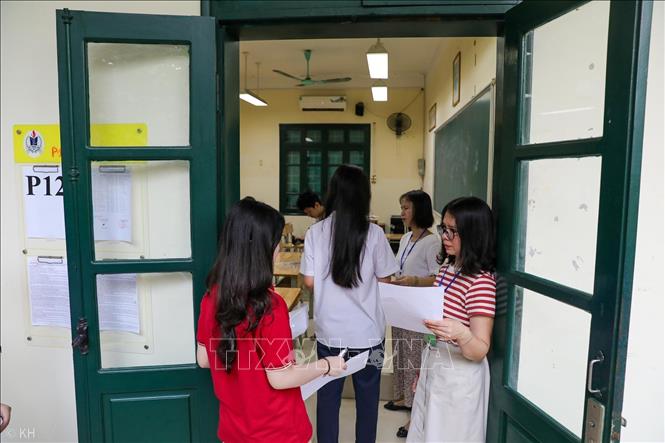 Giám thị đối chiếu thông tin thí sinh trước khi vào phòng thi tại điểm trường THPT Thăng Long (quận Hai Bà Trưng). Ảnh: Khánh Hoà - TTXVN