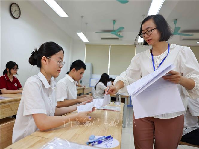 Giám thi phát giấy thi cho thí sinh tại điểm thi trường THCS Ngô Sĩ Liên (quận Hoàn Kiếm). Ảnh: Thanh Tùng - TTXVN