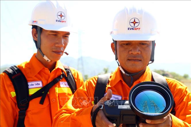 Công nhân đội truyền tải điện Bắc Bình (TTĐ Bình Thuận) dùng ống nhòm soi phát nhiệt kiểm tra đường dây 500kV Vĩnh Tân - Sông Mây. Ảnh: Huy Hùng - TTXVN