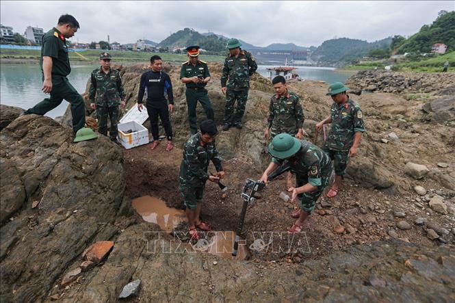 Lực lượng làm nhiệm vụ rà phá bom mìn, vật nổ tại khu vực lòng sông Đà, nằm cách không xa khu vực giới hạn an toàn của Nhà máy Thủy điện Hòa Bình. Ảnh: Trọng Đạt - TTXVN
