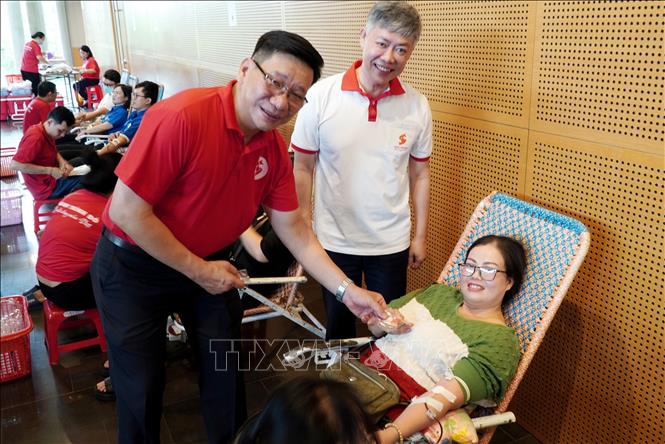 Phó Giáo sư, Tiến sĩ, bác sĩ Nguyễn Quang Tùng (trái), Phó Viện trưởng Viện Huyết học - Truyền máu Trung ương, Phó Ban tổ chức Chương trình “Hành trình Đỏ” quốc gia năm 2025 tặng huy hiệu giọt hồng tri ân cho các thành viên tham gia hiến máu. Ảnh: Lê Phước Ngọc - TTXVN