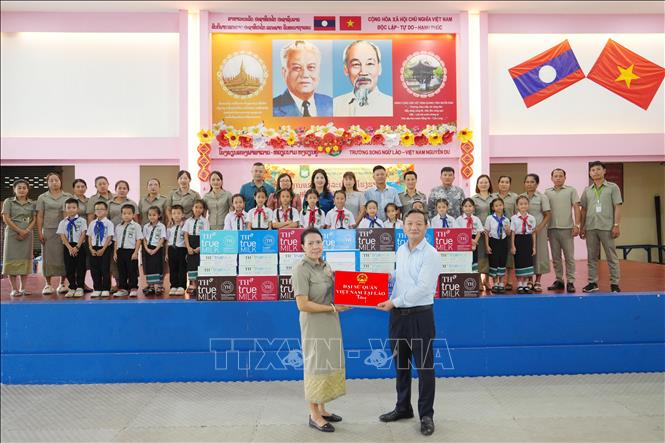 Đại sứ Nguyễn Minh Tâm cùng các thành viên trong đoàn trao tặng 50 thùng sữa cho các học sinh Trường song ngữ Lào - Việt Nam Nguyễn Du. Ảnh: Đỗ Bá Thành - PV TTXVN tại Lào