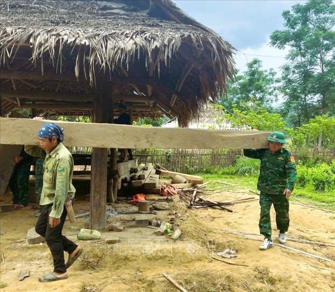 Trong đợt 1 từ ngày 12 đến 15/6, chiến sĩ Đồn biên phòng Môn Sơn (BĐBP Nghệ An) trực tiếp hỗ trợ 4 hộ gia đình ở bản Cò Phạt tháo dỡ nhà cũ, làm lán tạm, san ủi mặt bằng để xây móng và nền nhà. Ảnh: TTXVN phát