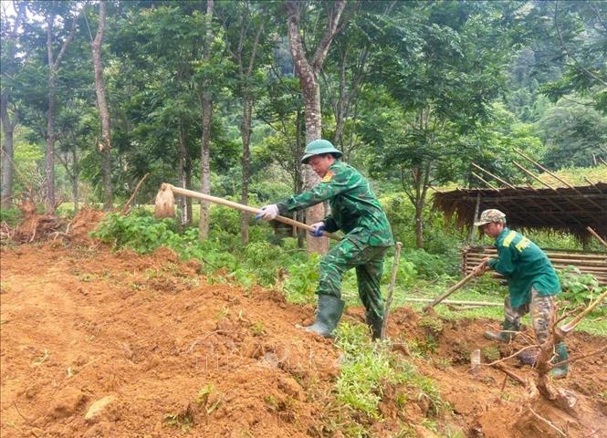 Lực lượng biên phòng Đồn biên phòng Môn Sơn (BĐBP Nghệ An) cùng người dân Đan Lai cuốc đất, san ủi mặt bằng để làm nền, móng xây dựng nhà ở mới. Ảnh: TTXVN phát