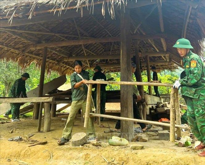Cán bộ, chiến sĩ Đồn biên phòng Môn Sơn (BĐBP Nghệ An) chung tay giúp đồng bào Đan Lai tháo dỡ nhà cửa, di chuyển đồ đạc. Ảnh: TTXVN phát 