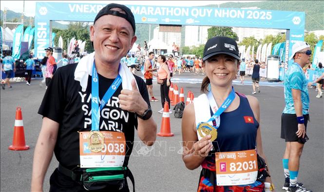 Đôi vận động viên người nước ngoài phấn khích khi chinh phục đường chạy với thành tích tốt. Ảnh: Lê Phước Ngọc – TTXVN 