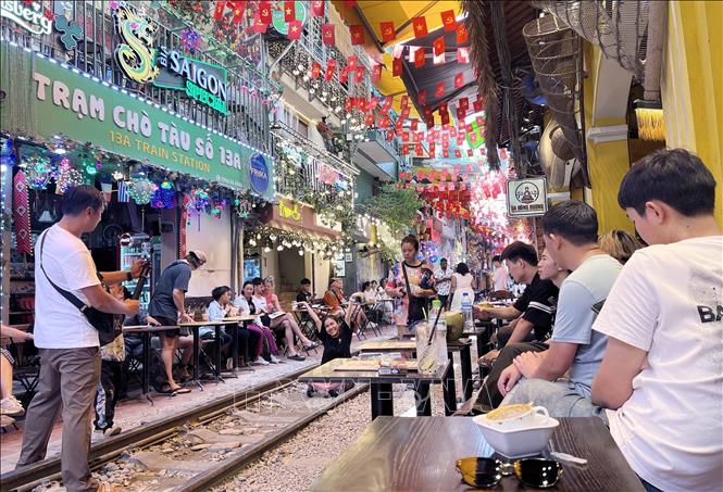 Du khách trải nghiệm cảm xúc ngay trên đường ray tàu hỏa ở phố cà phê đường tàu, sáng 15/6. Ảnh: Thành Phương - TTXVN