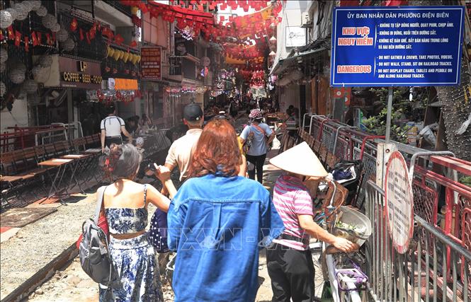 Du khách phớt lờ biển cảnh báo nguy hiểm khi đi lại trên tuyến đường sắt, sáng 15/6. Ảnh: Thành Phương - TTXVN