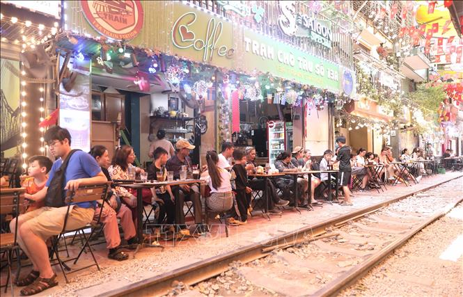 Du khách trải nghiệm cảm xúc ngay sát đường ray tàu hỏa ở phố cà phê đường tàu, sáng 15/6. Ảnh: Thành Phương - TTXVN