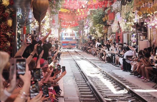 Du khách chen chúc tại các quán cà phê hai bên đường ray, háo hức chụp ảnh bất chấp nguy hiểm khi tàu đến. Ảnh: Thành Phương - TTXVN