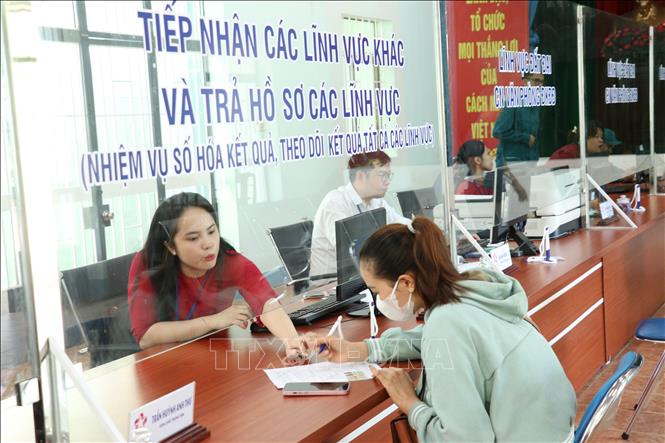 Hướng dẫn người dân làm thủ tục đăng ký hộ kinh doanh. Ảnh: Dương Chí Tưởng - TTXVN