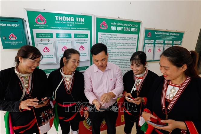 Cán bộ Ngân hàng Chính sách Xã hội huyện Ba Vì, Hà Nội, hướng dẫn tổ trưởng tổ tiết kiệm và vay vốn sử dụng phần mềm quản lý hộ vay trên thiết bị di động. Ảnh: Trần Việt - TTXVN
