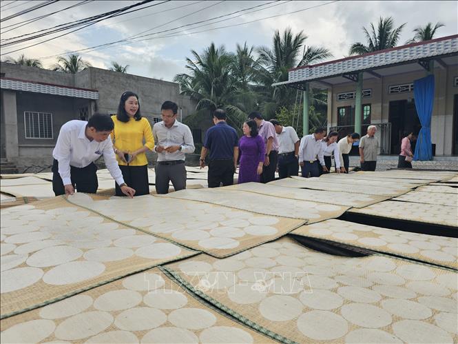 Các du khách trải nghiệm công đoạn phơi bánh phồng Sơn Đốc. Ảnh: Chương Đài - TTXVN