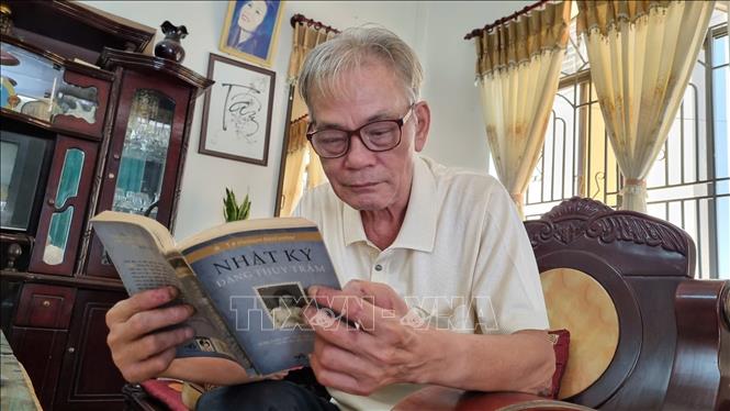 Ông Trần Đình Tâm (77 tuổi, nguyên lính Đại đội 120 đặc công huyện Đức Phổ), người từng được chị Trâm chữa bệnh đang đọc Nhật ký của chị Trâm. Ảnh: Đinh Hương - TTXVN
