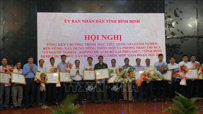 Ông Nguyễn Tuấn Thanh, Phó Chủ tịch UBND tỉnh Bình Định tặng bằng khen cho các tập thể và cá nhân đã có thành tích xuất sắc trong các phong trào thi đua giảm nghèo. Ảnh: Đình Quân-TTXVN