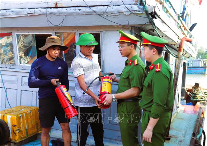 Lực lượng công an xã trao tặng bình cứu hỏa cho ngư dân và tuyên truyền về công tác phòng, chống cháy, nổ cho ngư dân tại Cảng cá Lạch Thơi (huyện Quỳnh Lưu). Ảnh: Xuân Tiến-TTXVN   