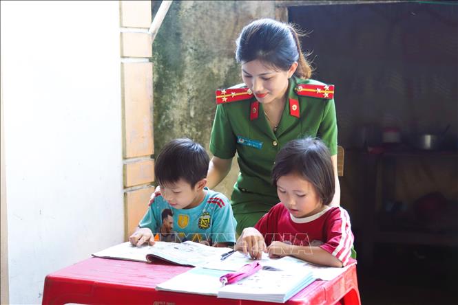 Nữ thượng úy công tác tại Công an xã Văn Hải (huyện Quỳnh Lưu, Nghệ An) hỗ trợ dạy học thêm cho các cháu học sinh là con em của ngư dân miền biển. Ảnh: Xuân Tiến-TTXVN 