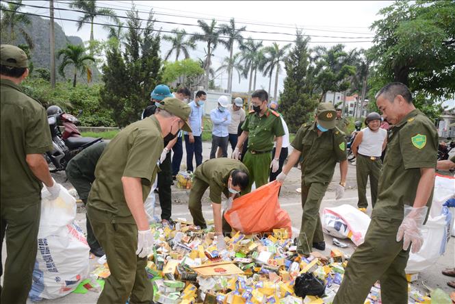 Lực lượng chức năng thu gom, phân loại các chủng loại các mặt hàng bị đổ bỏ để xử lý theo quy định của pháp luật. Ảnh: Thanh Vân - TTXVN