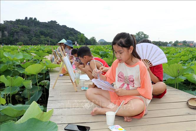 Thiếu nhi được gia đình cho đến các đầm sen ở Ninh Bình để vui chơi, vẽ tranh. Ảnh: Thùy Dung - TTXVN