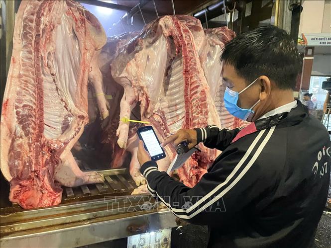 Cán bộ Đội quản lý an toàn thực phẩm số 9 kiểm tra thông tin tích hợp tại vòng truy xuất kèm theo. Ảnh: Hương Giang - TTXVN