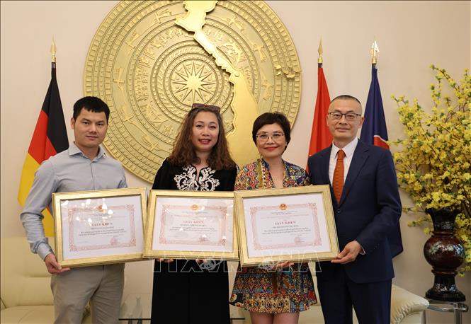 Đại sứ Vũ Quang Minh trao Giấy khen cho các phóng viên thường trú TTXVN tại Berlin. Ảnh: PV TTXVN tại Đức