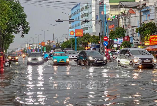 Các phương tiện di chuyển khó khăn trên đường Nguyễn Văn Cừ đang bị ngập do trận mưa chiều 20/6. Ảnh: Thanh Liêm - TTXVN