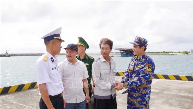 Ngư dân Tiêu Viết Bút (thứ 2 bên phải sang) bắt tay tạm biệt cán bộ, chiến sĩ trên đảo Trường Sa trước khi trở lại tàu cá. Ảnh: TTXVN phát