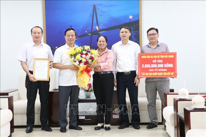 Phó Chủ tịch Ủy ban MTTQ Việt Nam tỉnh Bến Tre Đặng Thị Phượng tiếp nhận kinh phí xây dựng 50 căn nhà Đại Đoàn kết và trao hoa, thư cảm ơn cho Ủy ban MTTQ Việt Nam tỉnh Bắc Giang. Ảnh: Chương Đài  - TTXVN 