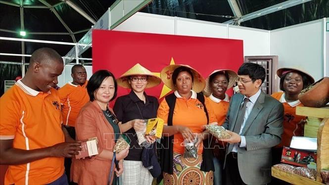 Đại sứ Lê Huy Hoàng và Phu nhân giới thiệu nhiều mặt hàng của Việt Nam như nông sản, đồ gia dụng, giày dép tới người dân Mozambique tại Hội chợ Thương mại quốc tế lần thứ 55 (FACIM) 2019. Ảnh: Đình Lượng - TTXVN