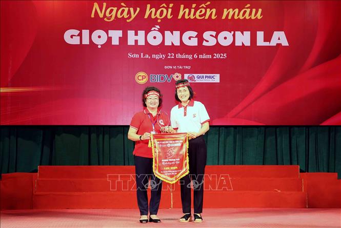 Phó Giám đốc Trung tâm Máu quốc gia (Viện Huyết học - Truyền máu Trung ương) Võ Thị Diễm Hà (bên phải) trao cờ lưu niệm và biểu trưng đơn vị tổ chức Chương trình Hành trình đỏ cho Chủ tịch Hội Chữ thập đỏ tỉnh Sơn La Cầm Thị Chuyên. Ảnh: Quang Quyết - TTXVN