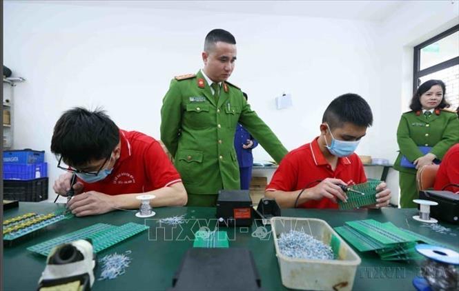 Cán bộ, chiến sĩ Phòng Cảnh sát điều tra tội phạm về ma tuý, Công an thành phố Hà Nội trực tiếp quản lý và hướng dẫn các học viên tại cơ sở cai nghiện ma tuý số 4 sản xuất linh kiện điện tử. Ảnh: Phạm Kiên - TTXVN