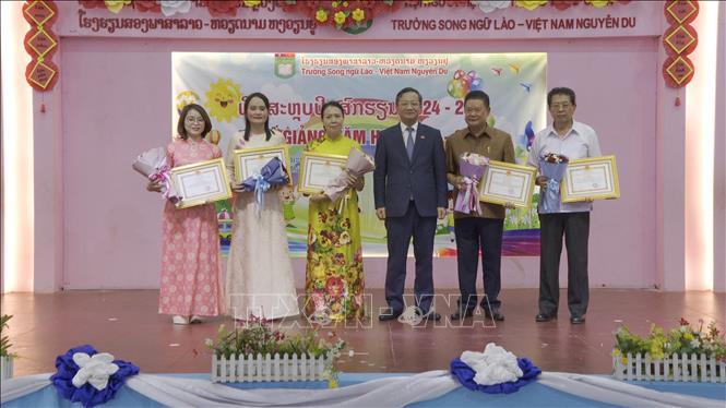 Đại sứ Việt Nam tại Lào Nguyễn Minh Tâm trao giấy khen cho Hội người Việt Nam thủ đô Viêng Chăn và Ban giám Hiệu nhà trường. Ảnh: TTXVN phát