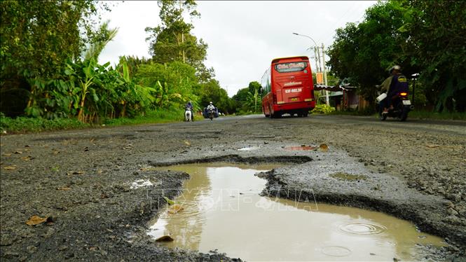 Nhiều cái hố sâu khoảng 20cm tồn tại trên Quốc lộ 61 tiềm ẩn nguy cơ tai nạn giao thông. Ảnh: Văn Sĩ - TTXVN                                  