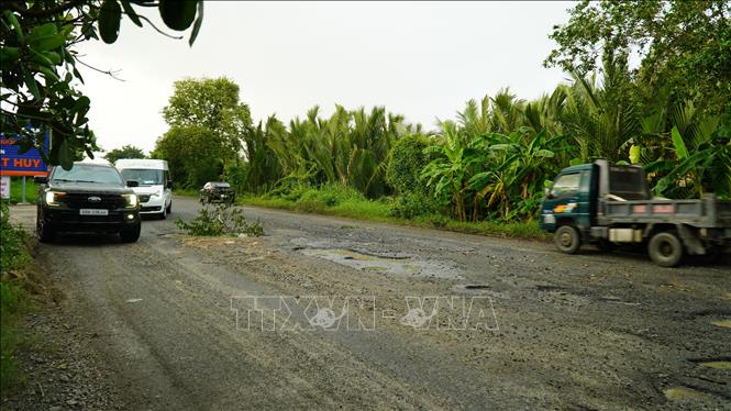 Quốc lộ 61 tồn tài nhiều ổ voi giữa đường khiến các phương tiện phải lấn sang phần đường của xe máy gây nguy hiểm giao thông. Ảnh: Văn Sĩ - TTXVN                       