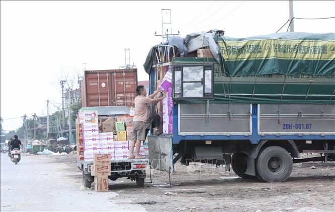 Hàng hoá có nhãn mác nước ngoài được trung chuyển sang các phương tiện nhỏ. Ảnh: Thành Phương – TTXVN