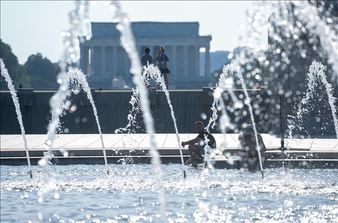 Người dân tránh nóng bên đài phun nước tại Washington, D.C., Mỹ, ngày 23/6/2025. Ảnh: THX/TTXVN