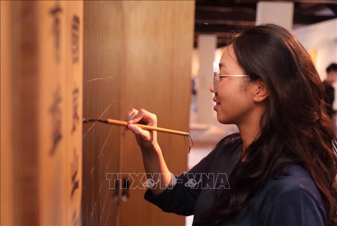 Thí sinh viết ước nguyện lên bức tường Thượng Điện tại Văn miếu - Quốc Tử Giám với hy vọng đạt được điểm cao. Ảnh: Thành Phương - TTXVN